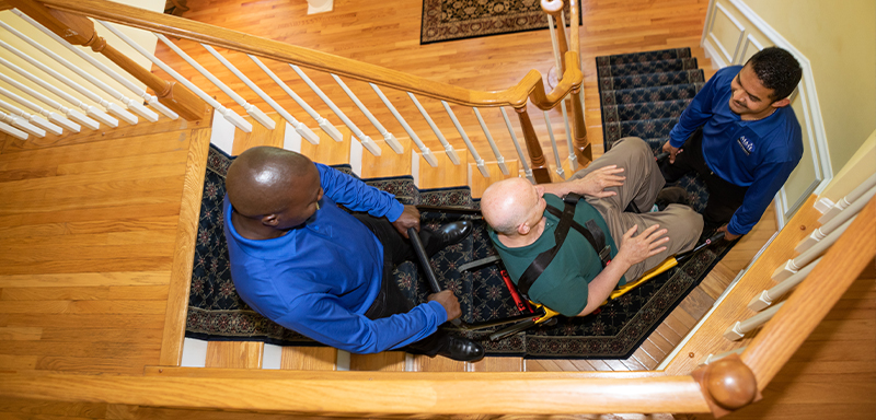 MML Staff Helping Man in Wheelchair up Stairs
